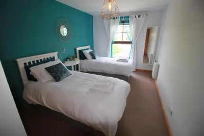 a bedroom with two beds and a blue wall at Six Stevenson House, Oban in Oban