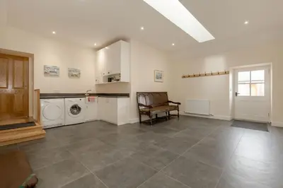a living room with a washing machine and a chair at Pant Farmhouse in Ayr