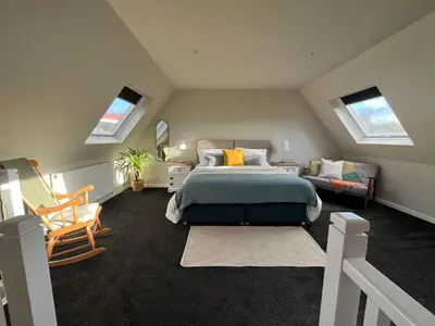 a bedroom with a bed and a couch and windows at Kilmory Garden by the Loch in Lochgilphead