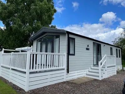 a white tiny house with a white fence at Lomond Woods Holiday Park in Balloch