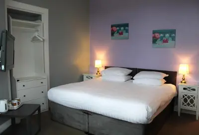 a bedroom with a bed with white sheets and two lamps at The Woodhouse Hotel in Largs