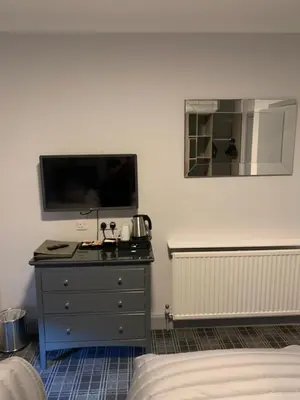 a bedroom with a dresser with a flat screen tv at The Royal Hotel in Stranraer