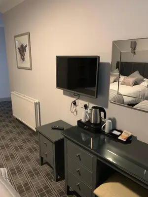 a hotel room with a desk with a television and a bed at The Royal Hotel in Stranraer
