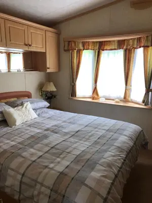 a bedroom with a bed and two windows at The Aspen 63 in Dunoon