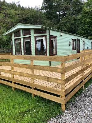 a green trailer with a wooden fence at The Aspen 63 in Dunoon