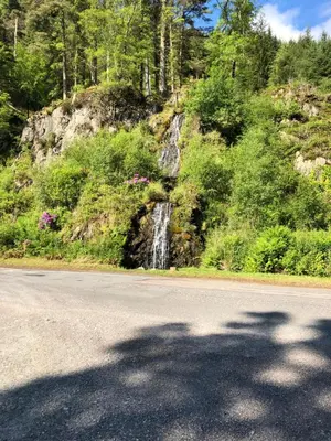 a road with a waterfall on the side of a mountain at The Aspen 63 in Dunoon