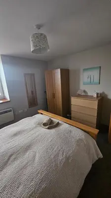 a bedroom with a large bed and a dresser at Modern 1 bed Apartment close to Campbeltown in Campbeltown