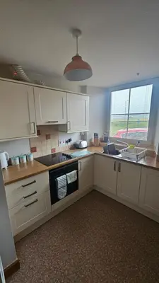 a kitchen with white cabinets and a large window at Modern 1 bed Apartment close to Campbeltown in Campbeltown