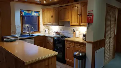 a kitchen with wooden cabinets and a black stove top oven at Beech Chalet in Glencoe