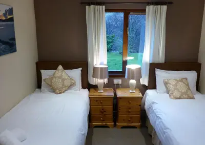 two beds in a room with two lamps and a window at Oak Tree Lodge in Ballachulish