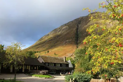 a house in front of a mountain with red flowers at Oak Tree Lodge in Ballachulish