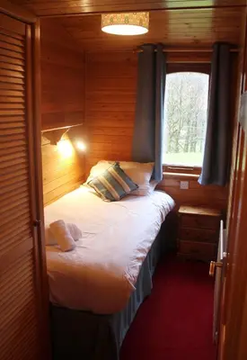 a small room with a bed with a window at Rowan Tree Lodge in Glencoe