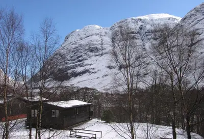 a cabin in front of a snow covered mountain at Rowan Tree Lodge in Glencoe