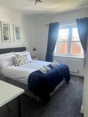 a bedroom with a bed with two towels on it at Home2Home Meadow Close in East Kilbride