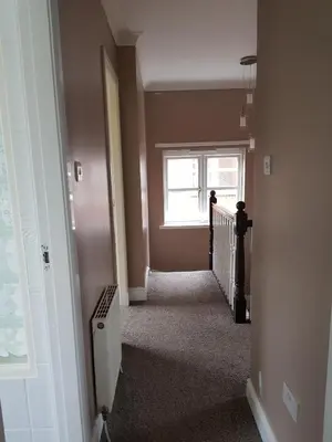 a hallway with a stairway with a window at Home2Home Meadow Close in East Kilbride