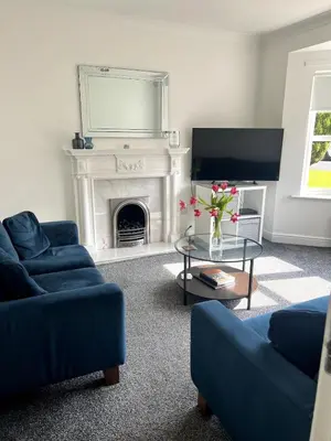 a living room with two blue couches and a fireplace at Home2Home Meadow Close in East Kilbride