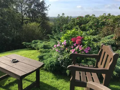 a wooden table and a bench next to flowers at Kilmeny in Ballygrant