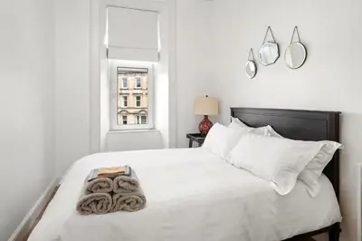 a white bedroom with a large bed with white pillows at Exceptional Central 1BR Apt - town square views in Oban