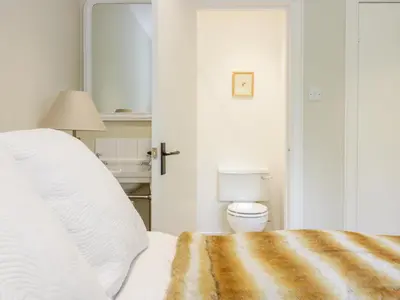 a white bedroom with a bed and a toilet at Gate Lodge in West Calder