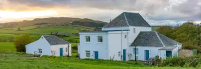 a group of white houses in a grassy field at Kilchrist Castle Cottages in Campbeltown