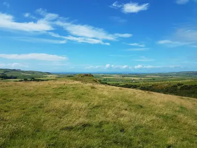 a field of grass with a blue sky and clouds at Kilchrist Castle Cottages in Campbeltown