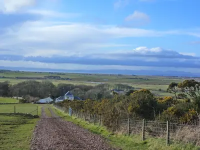 a dirt road in a field with a fence at Kilchrist Castle Cottages in Campbeltown