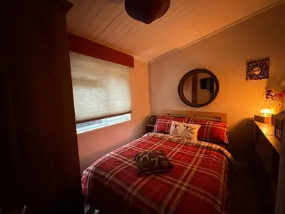 a bedroom with a bed with a red blanket and a mirror at Ramintoul Lodge in Glendevon