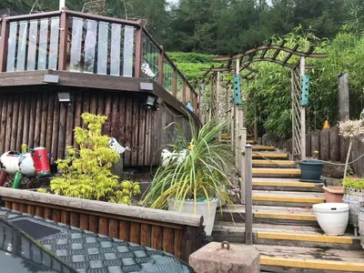 a wooden staircase leading to a garden with plants at Ramintoul Lodge in Glendevon