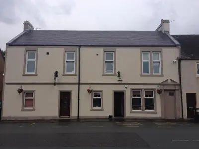 a white house with a black roof on a street at The Victoria Inn Blythswood Snug in Falkirk