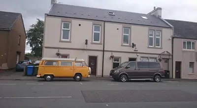 two cars parked in a parking lot in front of a house at The Victoria Inn Blythswood Snug in Falkirk