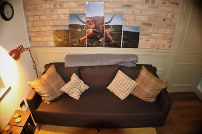 a couch in a living room with paintings on the wall at The Victoria Inn Blythswood Snug in Falkirk
