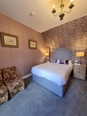 a bedroom with a large bed and a chair at Corriemar House in Oban