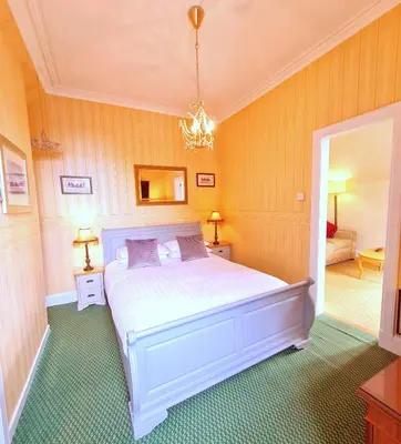 a bedroom with a white bed and a chandelier at Corriemar House in Oban