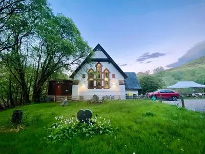 a house on a hill with a green field at Inversnaid Bunkhouse in Inversnaid