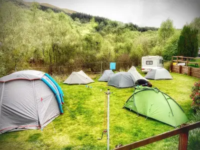 a group of tents sitting in a grass field at Inversnaid Bunkhouse in Inversnaid