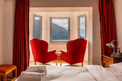 a bedroom with two red chairs and a window at The Lodge on the Loch by OYO in Onich