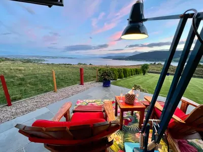 a patio with a table and chairs and a lamp at Knockderry Lodge -Private Luxury pet-friendly accommodation in Scotland with hot tub in Cove