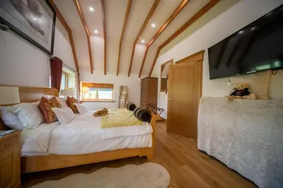 a bedroom with a large bed and a flat screen tv at Knockderry Lodge -Private Luxury pet-friendly accommodation in Scotland with hot tub in Cove