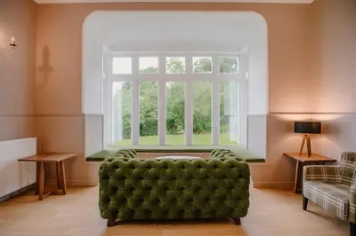 a living room with a green couch in front of a window at Rowardennan Youth Hostel in Rowardennan