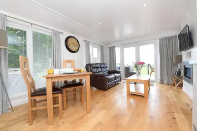 a living room with a table and a chair at Super King Lodge-Sleeps 2-HotTub-Sea View in Langbank
