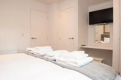 a pile of towels sitting on top of a bed at Super King Lodge-Sleeps 2-HotTub-Sea View in Langbank