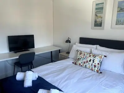 a bedroom with a bed with a desk and a television at Meadow House- Driveway Parking and Fireplace in East Kilbride