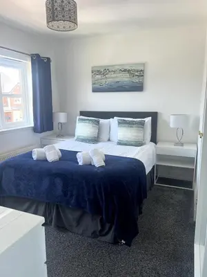 a bedroom with a large bed with a blue blanket at Meadow House- Driveway Parking and Fireplace in East Kilbride