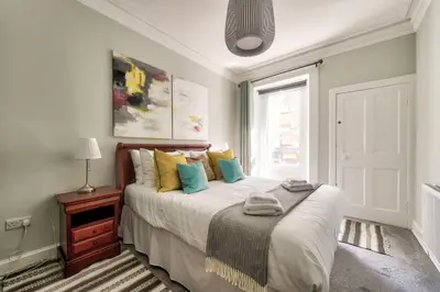 a bedroom with a large bed with colorful pillows at GuestReady - Spacious and Beautiful 2BR Flat in Morningside in Edinburgh