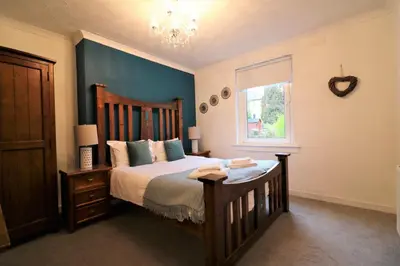 a bedroom with a large bed with a wooden headboard at Signature - Bruce Terrace Lower in High Blantyre