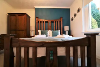 a bedroom with a large bed with a wooden frame at Signature - Bruce Terrace Lower in High Blantyre