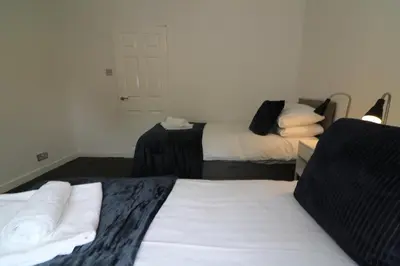 a room with two beds and a room with two at Signature - New View Place in Bellshill