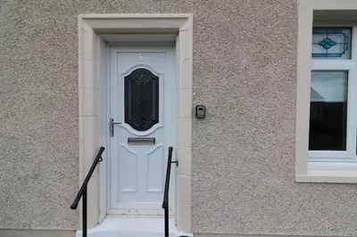 a white door on a building with stairs at Signature - New View Place in Bellshill