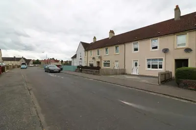 a street with houses and a car parked on the road at Signature - New View Place in Bellshill