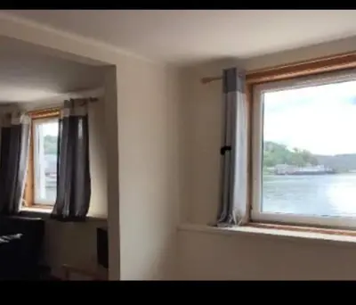 a room with a window with a view of the water at Panoramic Harbour View Apartment in Oban